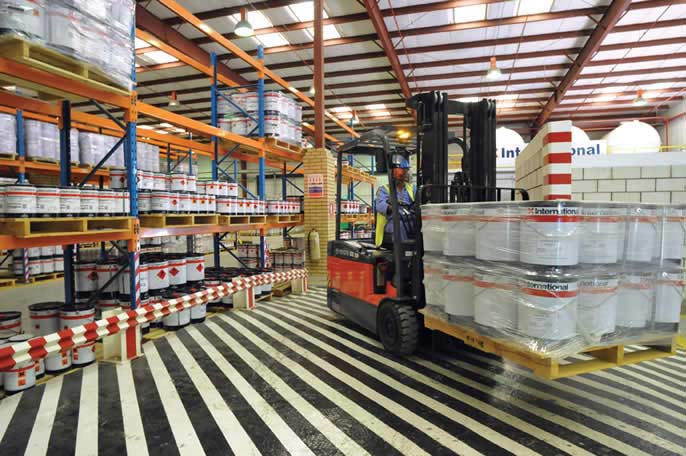 Forklift moving a pallet of International coating pails inside the IWC warehouse