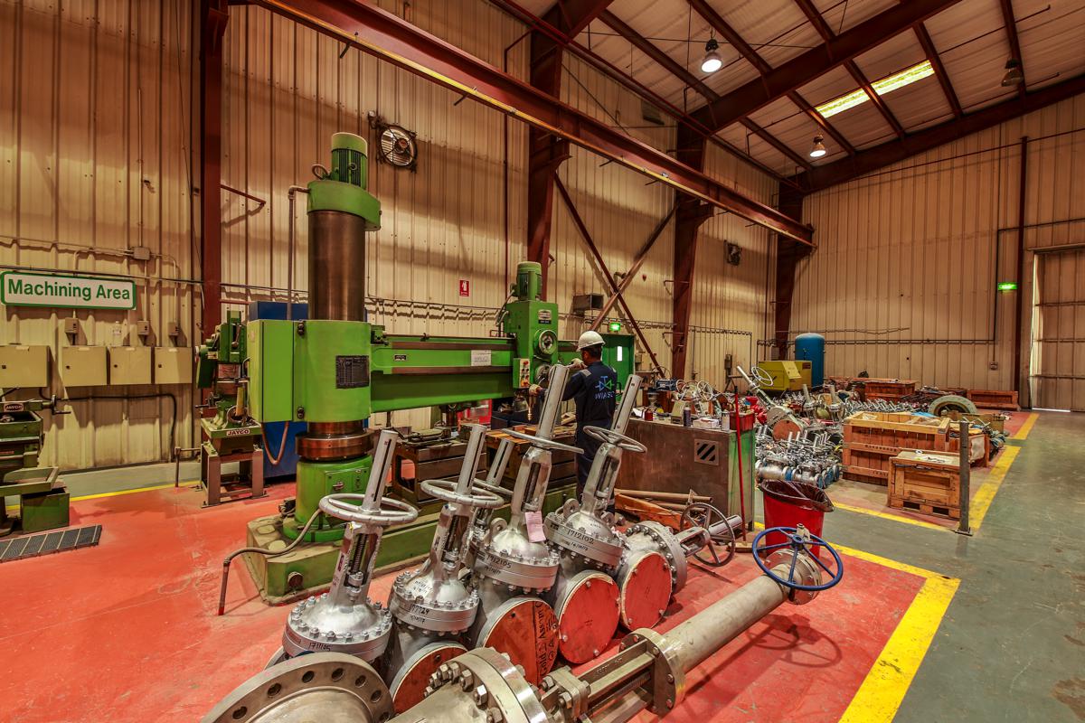The machining area, a technician working at the radial arm drill with gate valves in the foreground