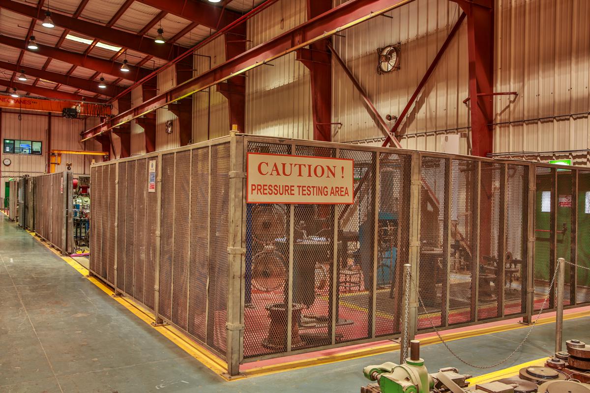 The pressure testing area, enclosed behind mesh screens and marked with a caution sign