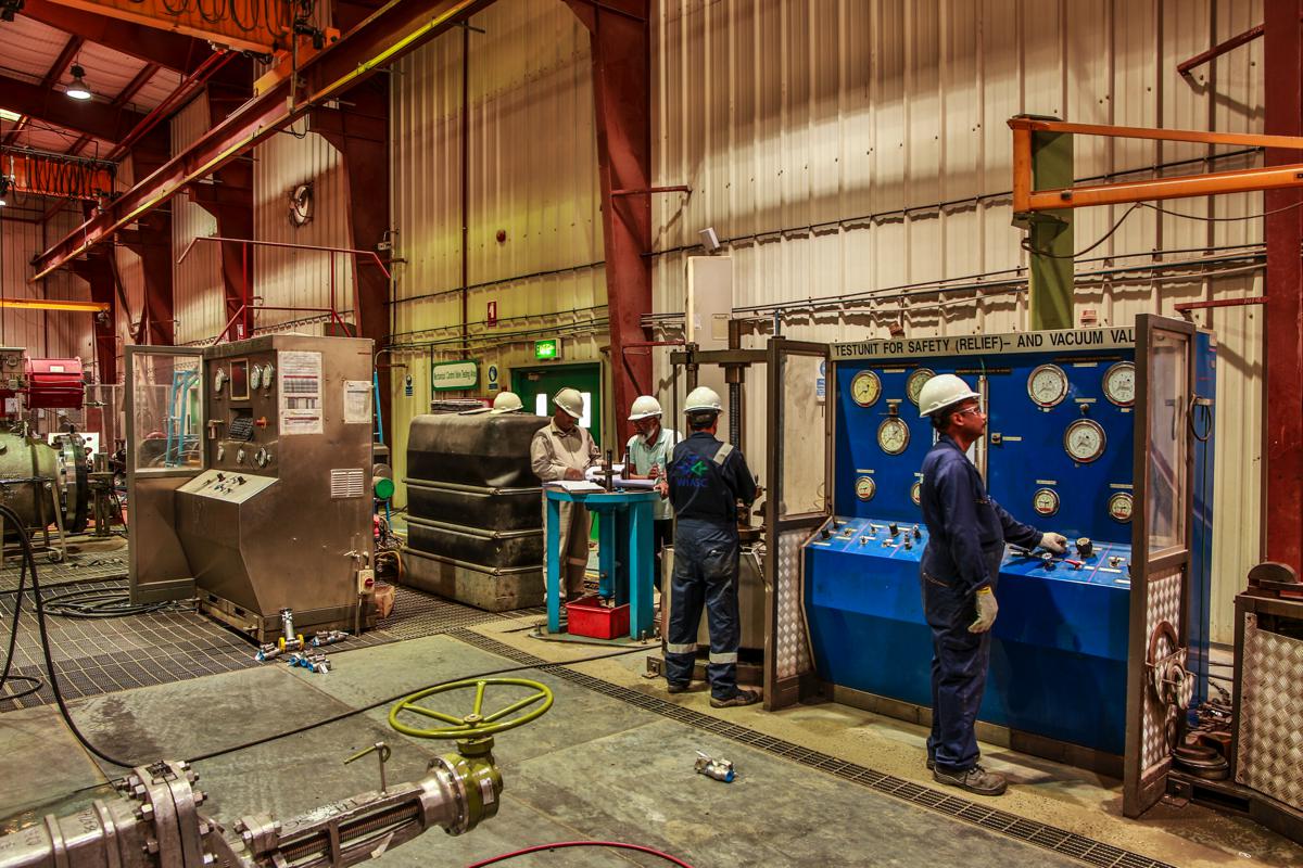 Technicians at the test unit for safety (relief) and vacuum valves, working the gauge panel