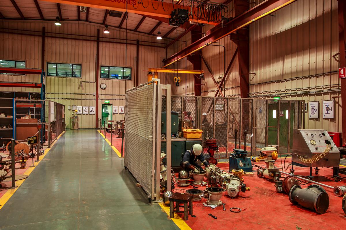 A technician stripping actuator assemblies in the workshop aisle, the quarantine area beyond