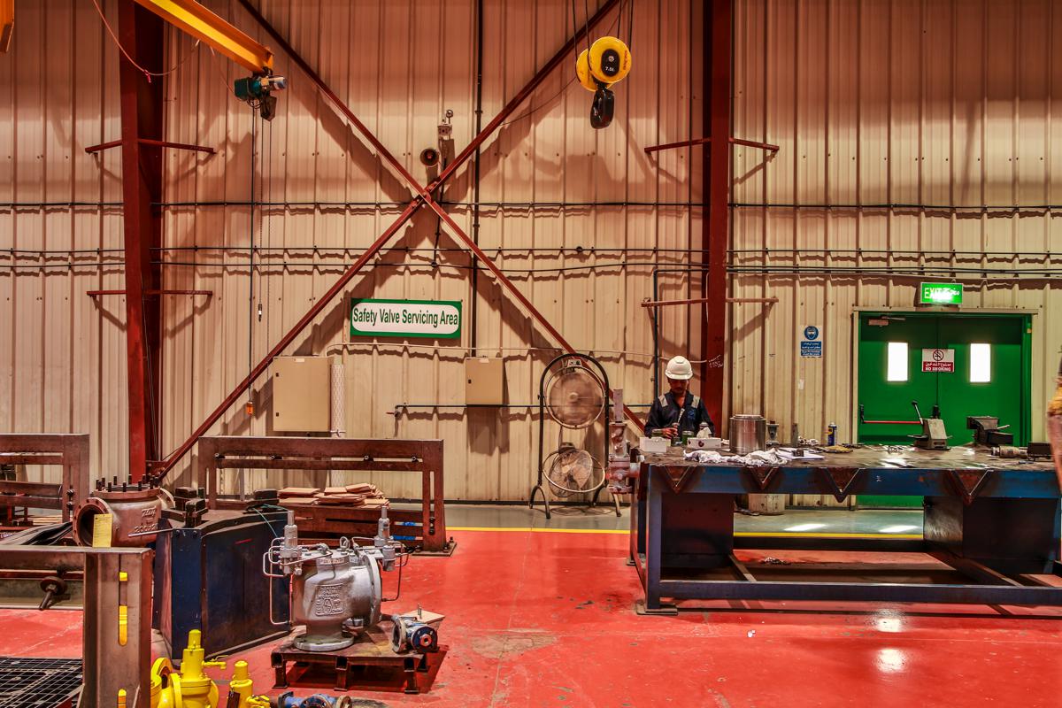 The safety valve servicing area, with relief valves in the foreground and a technician at the bench