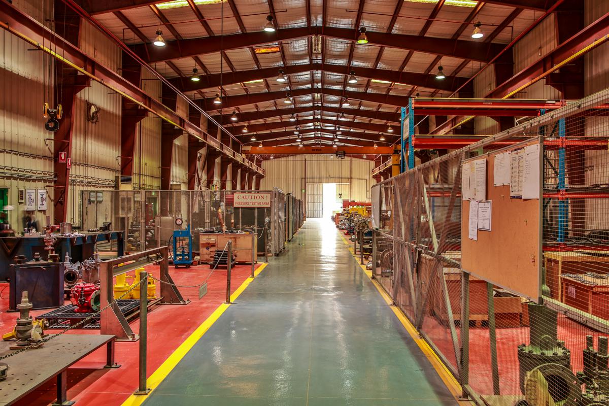 A view down the length of the workshop toward the open door, the pressure testing area to the left