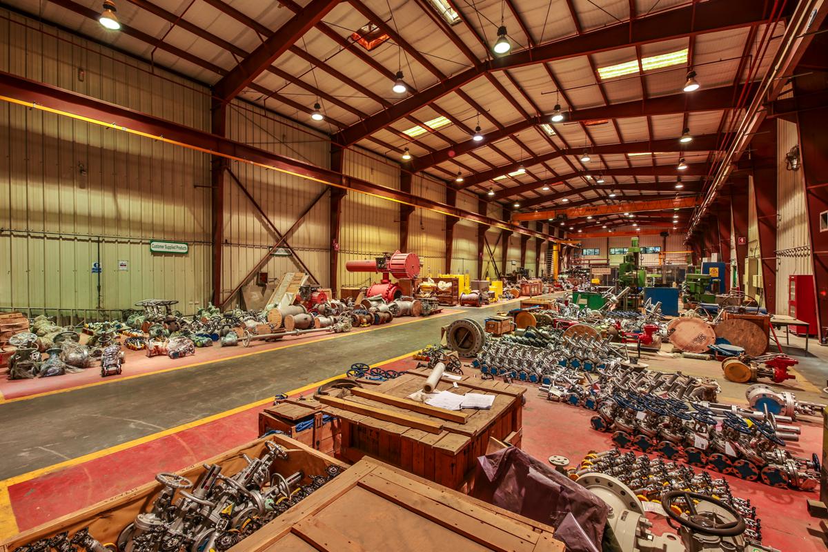 A wide view across the workshop, valves and crated assemblies either side of the walkway