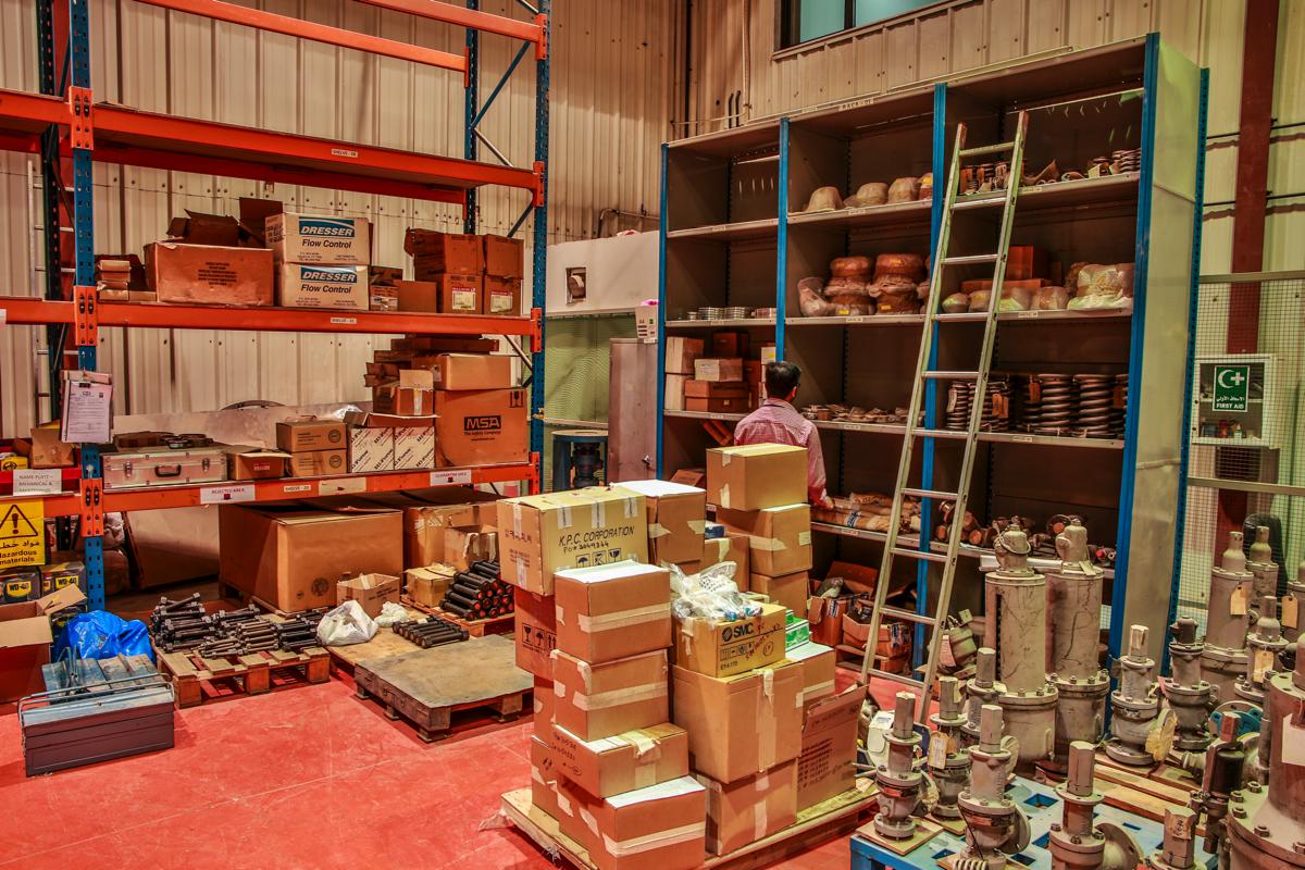 The spares store, shelves of parts boxes with safety valves stacked on a pallet in front