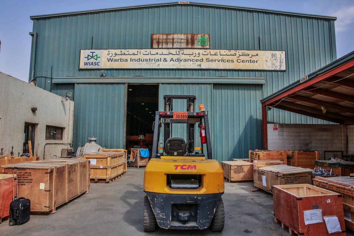 A forklift on the apron outside the workshop door, crated valves either side