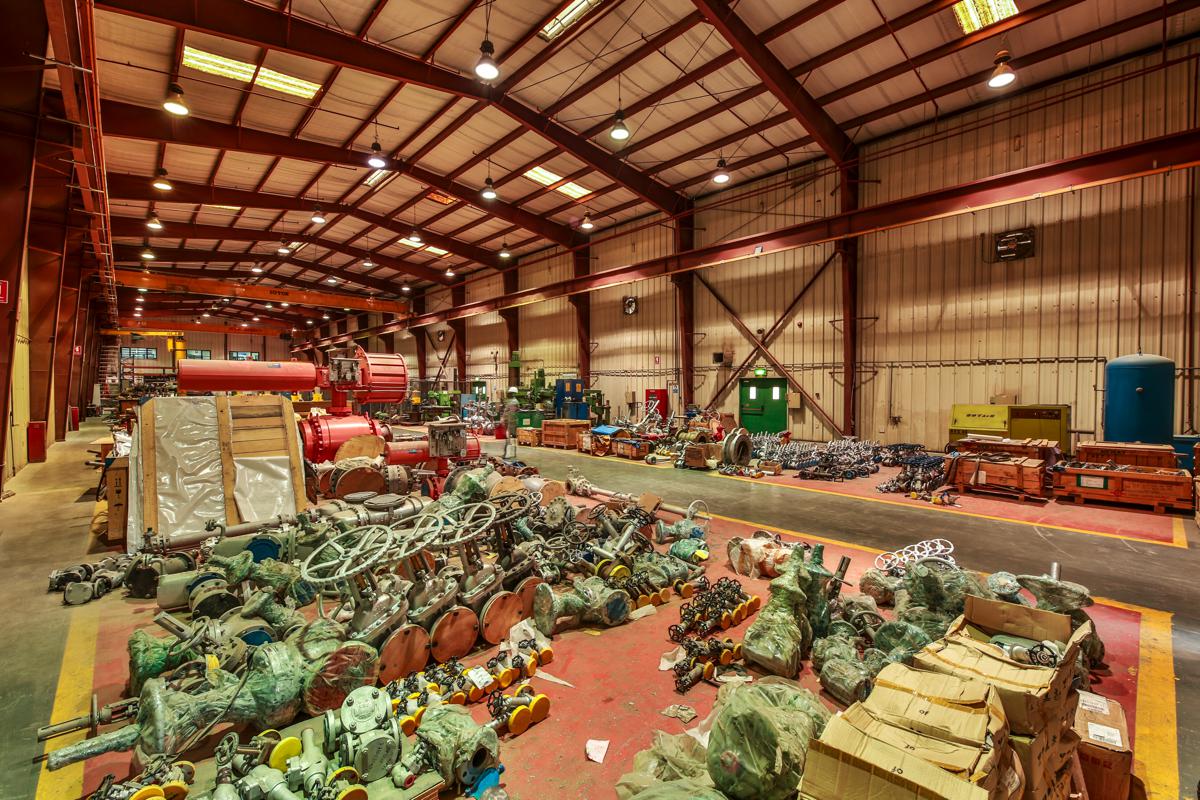 Wrapped valves and actuators stacked on the workshop floor, machining bays beyond